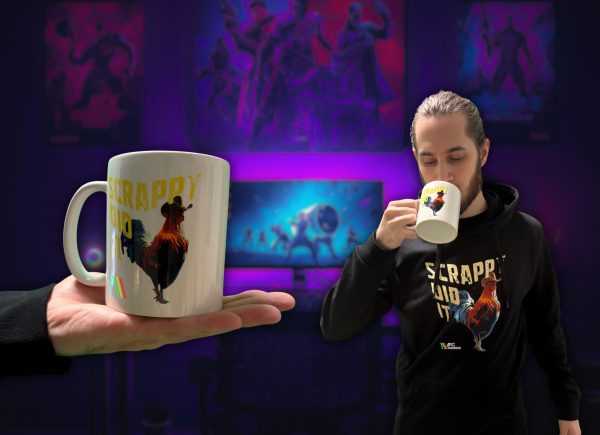 Hrnek ARC Raiders Scrappy Did It na dlani a muž v mikině se stejným motivem, který z hrnku pije
