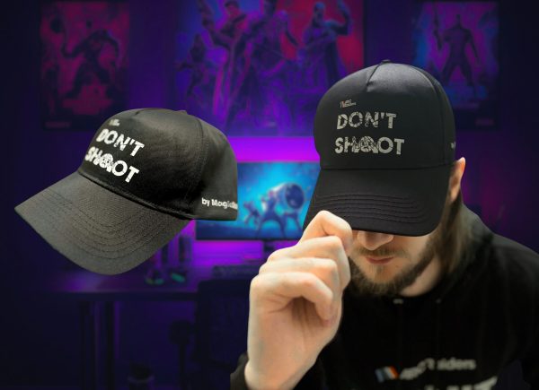 Černá kšiltovka ARC Raiders Don't Shoot – samotná kšiltovka z boku a muž, který si ji nasazuje, vpředu bílý nápis DON'T SHOOT