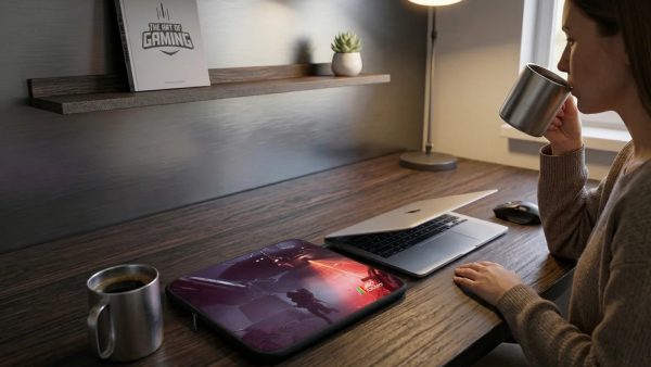 Obal na notebook ARC Raiders na dřevěném stole vedle notebooku a hrnku