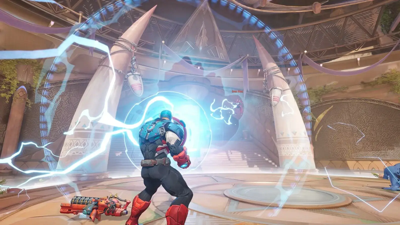 Captain America se štítem v elektrických výbojích v hale se sloupy ve tvaru klů, v pozadí Iron Man