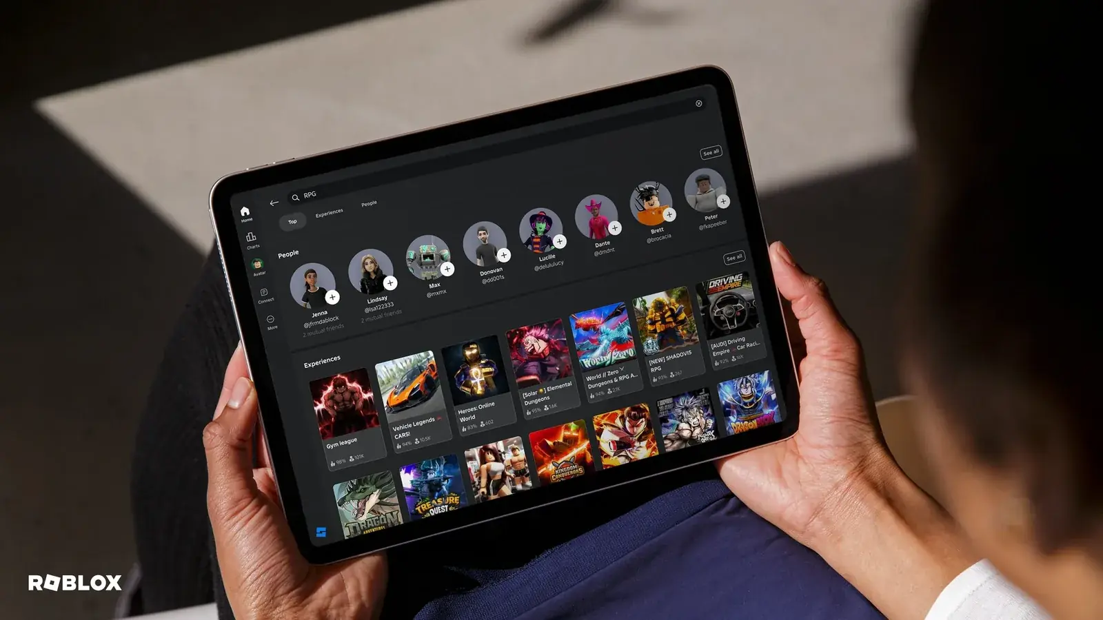 Ruce drží tablet s aplikací Roblox