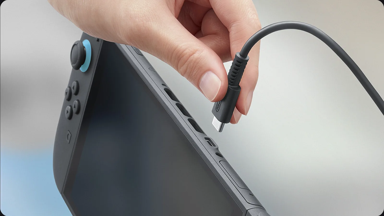 Ruka zapojuje USB-C kabel do horního portu Switch 2